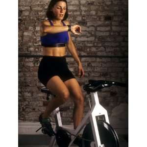 Young Woman Exercising on a Stationary Bike Checking her Heart Rate 